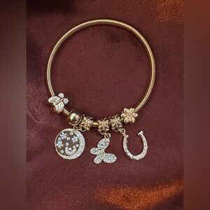 BEBE 
Gold-Tone stretch Charm Bracelet with Crystal Butterfly, Disc & Horseshoe